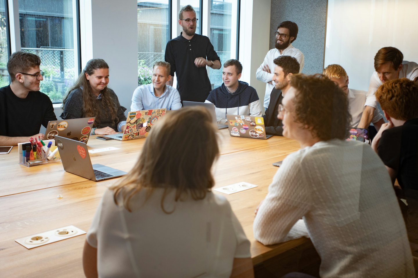 Young professionals collaborating around a table with laptops.